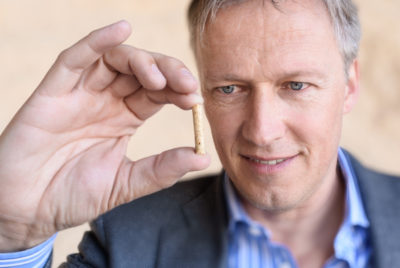 Peter Schweinberg hält ein Pellet in der Hand